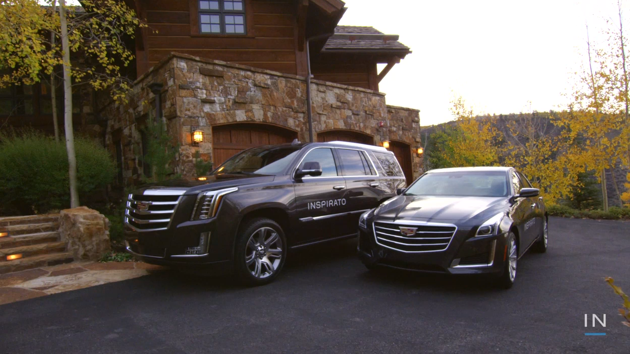 Image of two branded Inspirato Cadillacs parked in front of a house