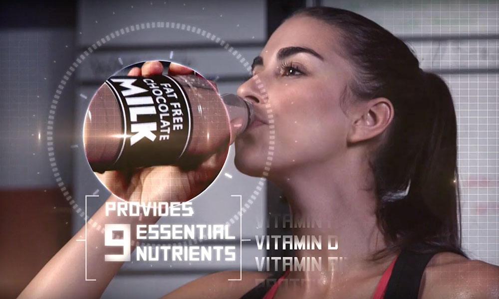 Woman drinking from a fat free chocolate milk bottle with a label indicating 9 essential nutrients.