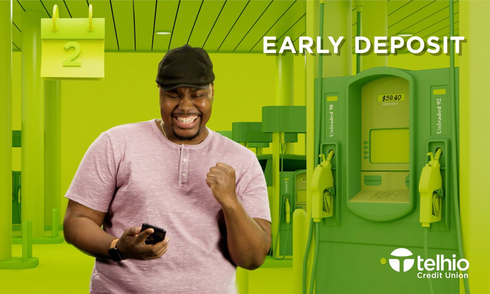 A man in a pink shirt and black cap smiling while looking at his phone, with graphic ATM machines in the background and text 'EARLY DEPOSIT'.
