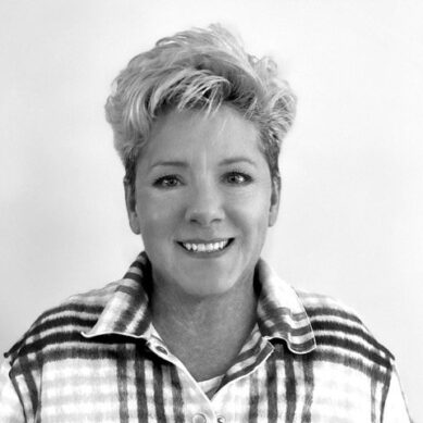 Portrait of woman with short blonde hair smiling wearing a flannel shirt
